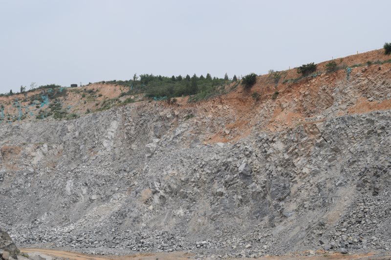 Panoramic hillside view — quarry above, factory below